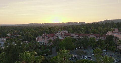 Beverly Hills , CA , United States - 06 06 2022: Flying Through Palm Trees Towards the Historic Pink Beverly Hills Hotel, Gorgeous Chateau in the Warm Sunset