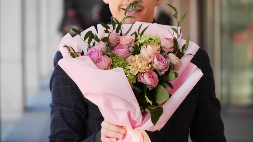 Young man with bouquet of beautiful flowers outdoors, closeup. Slow motion effect Royalty-Free Stock Footage #1091198997