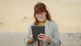 Middle age woman business executive using touchpad at street