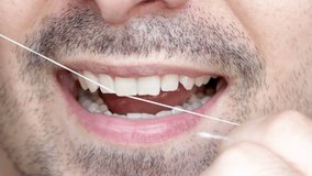 close up 4k video young man mouth,smiling and flossing teeth.beautiful smile, bearded male.natural small front teeth. dental care concept.oral hygiene, daily routine,morning or evening cleaning