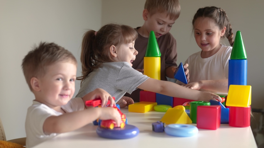 kids girl and baby boy play in kindergarten. a group of children play toys cubes and cars on the table in kindergarten. happy family indoor preschool education concept. nursery baby toddler home Royalty-Free Stock Footage #1091204239