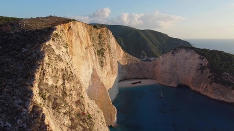 Aerial drone view of the Navagio beach (Shipwreck beach) on the Ionian Sea coast of Zakynthos, Greece. Rocky cliffs, alone boat, beach without people, sunset, sunrise.