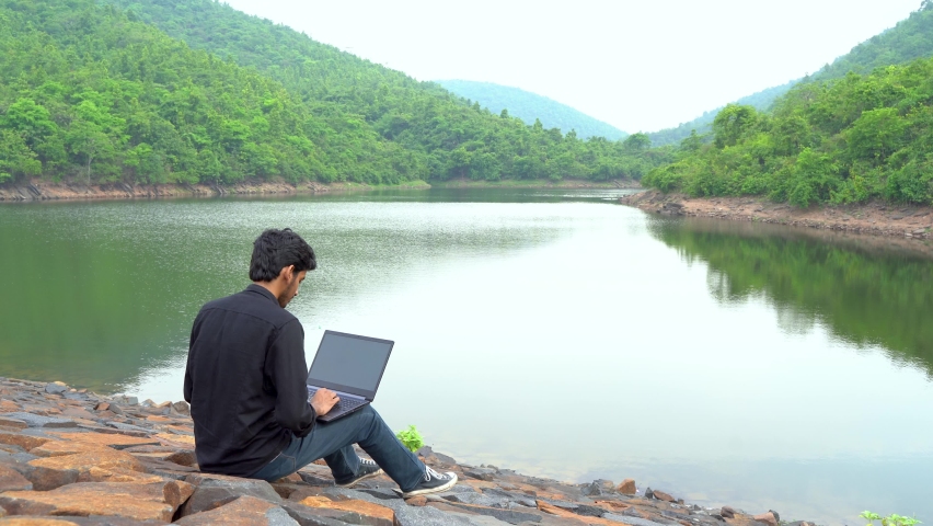 Young man working on a laptop and sitting in the nature, Workation and Digital Nomad concept. | Shutterstock HD Video #1091204877