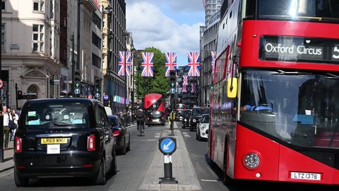 LONDON - May 16, 2022: Oxford Street decorated with Union Jack flags for the Jubilee with Double Decker Buses and Taxis driving past