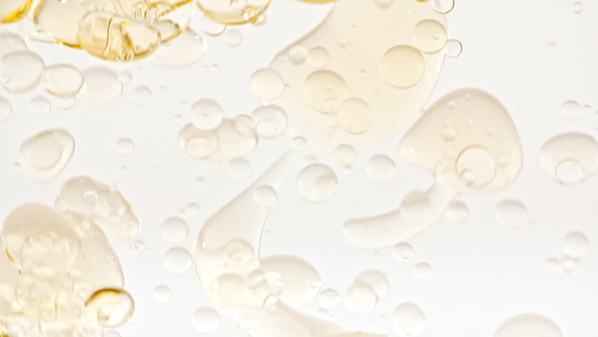 Slow Motion of Moving Yellow Golden Oil, Air Bubbles in Water Rising up on Light White Background. Transparent cosmetic gel fluid with bubbles. Macro Shot.