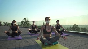 Fit sporty young woman wear medical face mask for safety meditating keeping social distance with female friends practicing yoga fitness exercise together on sunrise at retreat group class outdoors. - Powered by Shutterstock - Get 15% off with code: PIKWIZARD15