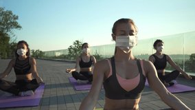 Sporty young woman wearing face mask for safety meditating keeping social distance with female friends practicing yoga fitness exercise together on sunrise at retreat group class outdoors. - Powered by Shutterstock - Get 15% off with code: PIKWIZARD15