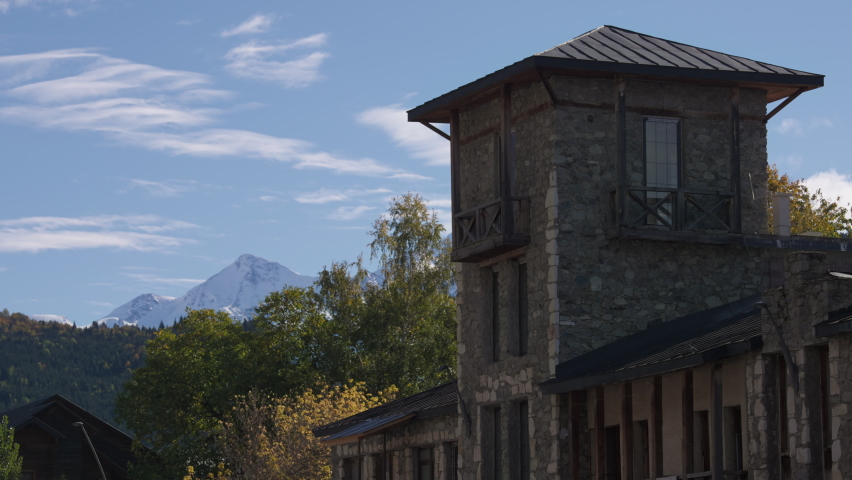 Ancient stone tower in the old town in Georgia, with snowy mountain peaks in the background. Slow motion.