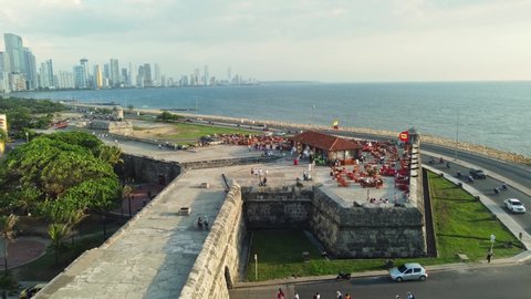 Cartagena, Colombia - May 09 2022: Aerial drone footage of people enjoy a drink and the view on the famous Cafe de Mar on the fortification of the colonial old town of Cartagena by the Caribbean sea. 
