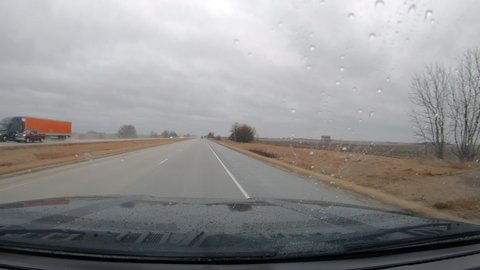 POV driving on an interstate in a rural area of Illinois on a cloudy rainy day in early spring near the Quad Cities; concepts of rain, travel and transportation