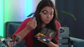 Beauty blogger Influencer is showing eye shadow palette and presenting cosmetics products. Teenage girl looking at the camera while recording a video. making video tutorial and live streaming. 4k