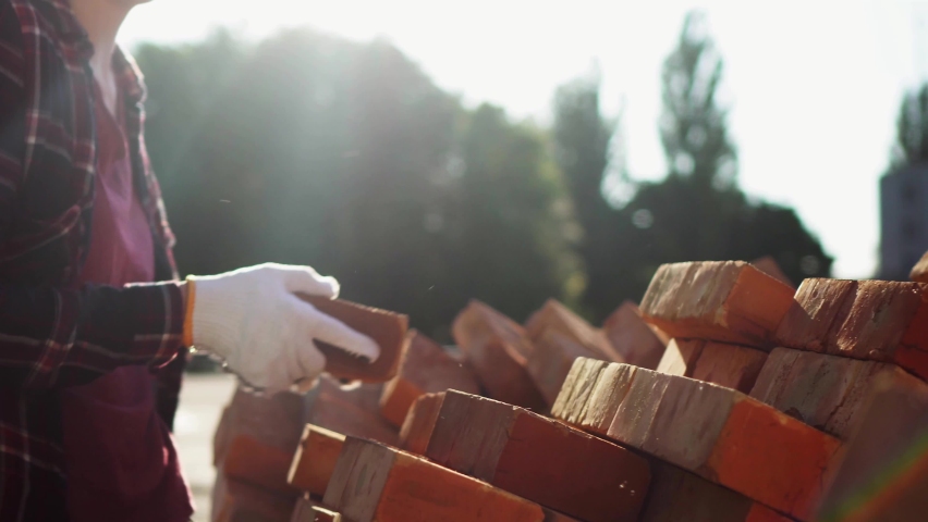 Construction company worker contractor loader unloads a warehouse a bunch of bright orange bricks, Builder
