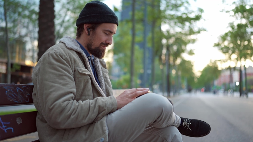 Pleased man wearing hat dancing and listening music in the city