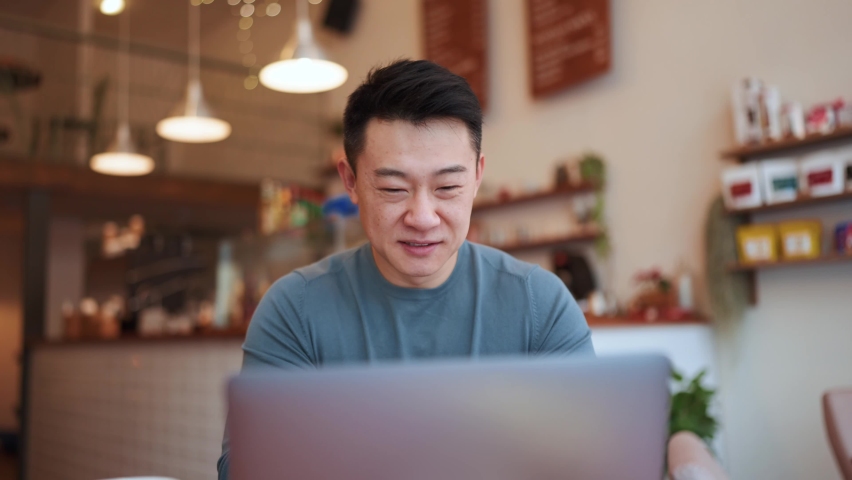 Happy Asian young man working by laptop in the cafe | Shutterstock HD Video #1091222015