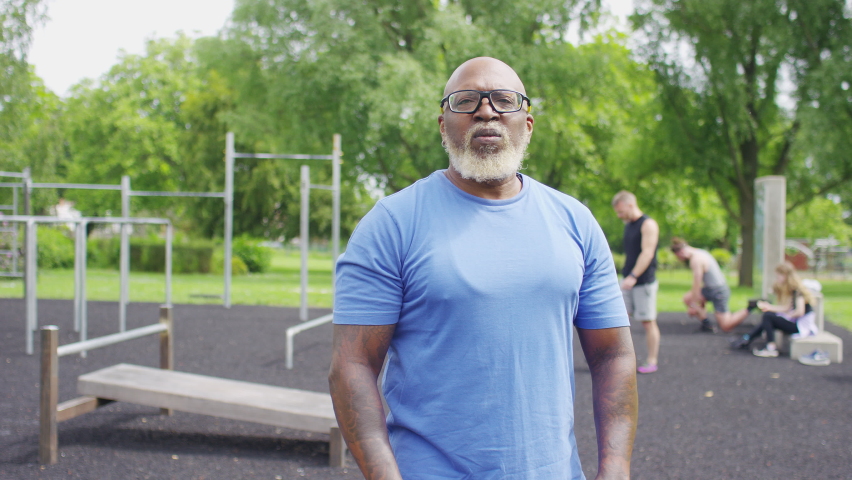 Portrait of confident, attractive, muscular senior black man looking to camera, smiling and folding his arms, in slow motion - version 2 Royalty-Free Stock Footage #1091222913