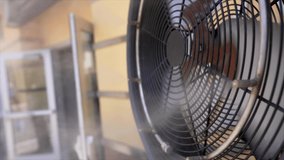 This close up video shows a side view of an outdoor misting fan in slow motion.