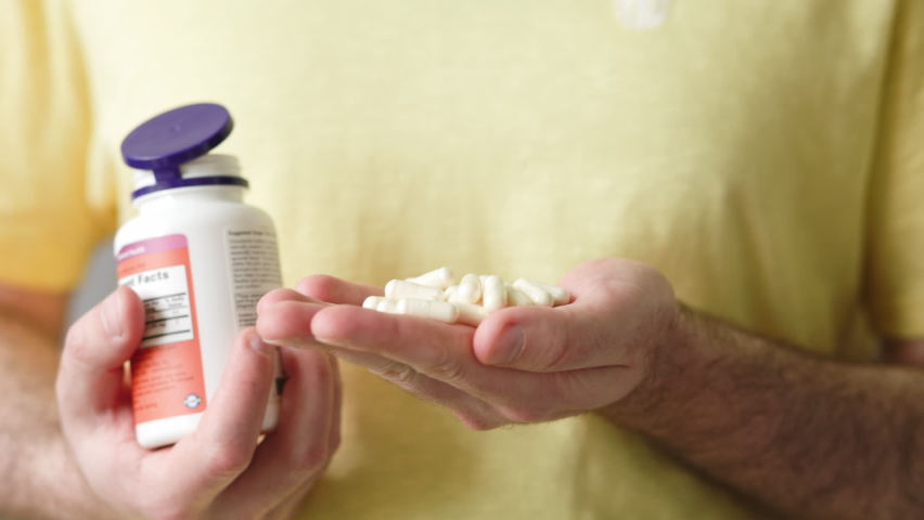 A man pours pills or vitamins from a jar into the palm of his hand. Close-up. The concept of health and dietary supplements. Royalty-Free Stock Footage #1091224037