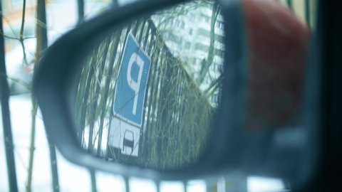 Parking road sign in a rear view mirror of a car