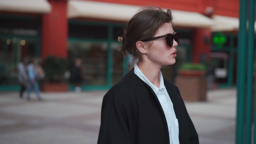 Middle shoot beautiful caucasian woman talking some thing dressed black coat standing outdoor city street. TV interview concept. 