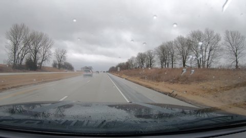 POV thru the windshield and active windshield wipers during a heavy rain while driving on Interstate 74 in a rural area of Illinois; concepts of rain, travel and transportation