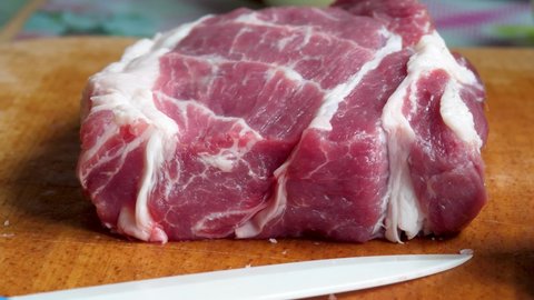 Raw pork meat on chopping board. juicy uncooked organic food for barbecue or BBQ. Culinary name for meat of domestic pig. Most commonly consumed meat worldwide. White kitchen knife 