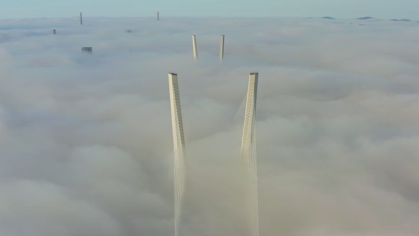 Tops of the pylons of the Golden Bridge in the dawn fog in Vladivostok. Suspension bridge concrete piers. Sunrise. Modern cable-stayed construction. Russia. Drone view
