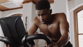 Fit and healthy black male cycling on exercise bike at an indoor fitness gym. - Powered by Shutterstock - Get 15% off with code: PIKWIZARD15