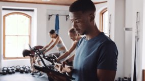 Confident Young adult black male using tablet at an indoor fitness gym. Fitness professional promoting healthy lifestyle. - Powered by Shutterstock - Get 15% off with code: PIKWIZARD15