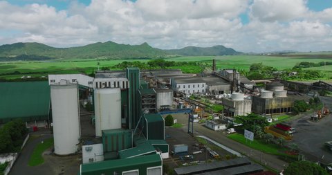 Aerial view of sugar factory in green sugarcane fields on Mauritius island. Sugar production.