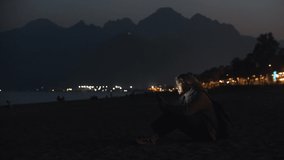 Blonde man in beige hoodie sitting on the night beach and texting on his phone - Powered by Shutterstock - Get 15% off with code: PIKWIZARD15