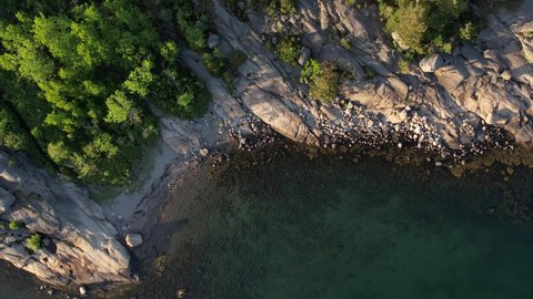 Flying over rocky coastline with a drone. Aerial 4K video view on the blue sea and white rocky coast with trees.