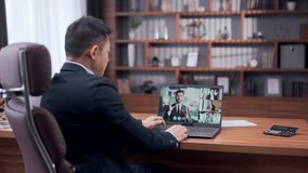 Rear view asian businessman holds a business meeting looking at monitor laptop screen remote, corporate web camera video conference call diverse colleagues team leader discussing project issues online