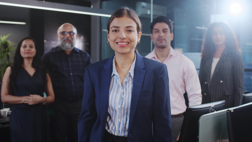 An attractive confident happy smiling diverse Asian Indian corporate formal female standing with mixed Gender office employees or business people with crossed or folded arms looking at the camera. Royalty-Free Stock Footage #1091264295