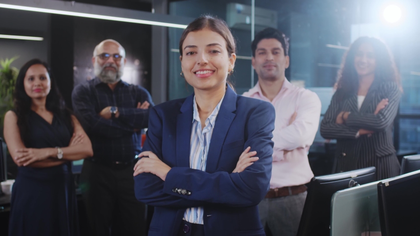 An attractive confident happy smiling diverse Asian Indian corporate formal female standing with mixed Gender office employees or business people with crossed or folded arms looking at the camera. | Shutterstock HD Video #1091264295