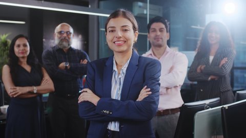 An attractive confident happy smiling diverse Asian Indian corporate formal female standing with mixed Gender office employees or business people with crossed or folded arms looking at the camera. Video de stock