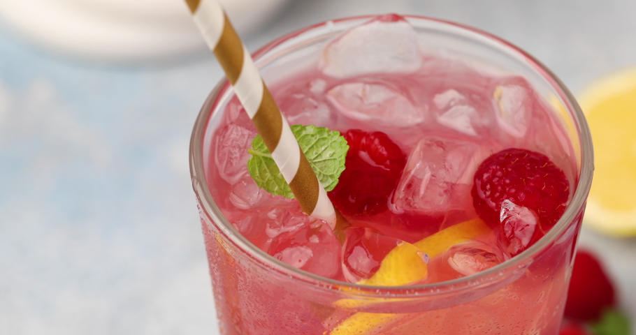 Spring or summer refreshing cold cocktail or mocktail with berries and lemon, raspberry lemonade being stirred with a spoon Royalty-Free Stock Footage #1091265023