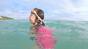 slow motion video - asian cute little girl wearing goggles playing outdoor swimming pool in water on tropical beach at Kenting of Taiwan while summer vacation