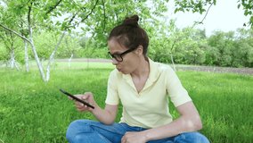 Beautiful young woman with a smartphone in the hands, sitting in the park