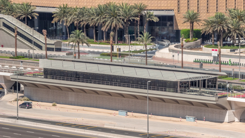 Futuristic building of Dubai tram station and shopping mall behind in Dubai Marina aerial timelapse. Traffic on Sheikh Zayed road highway, United Arab Emirates