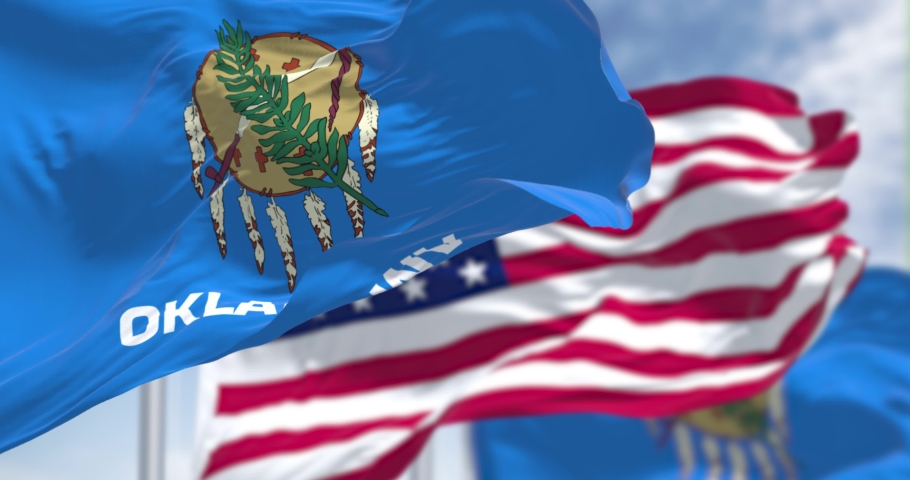 The Oklahoma state flag waving along with the national flag of the United States of America. Seamless loop in slow motion. Oklahoma is a state in the South Central region of the United States