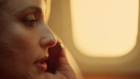 Beautiful woman chatting phone at porthole closeup. Smiling passenger on trip finishing smartphone talk with family business partner. Focused middle aged executive traveling working on private jet. - Powered by Shutterstock - Get 15% off with code: PIKWIZARD15