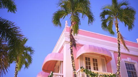 Naples, Florida downtown area in evening with colorful pastel pink architecture building looking up with Christmas holiday decoration lights on palm trees Video Stok