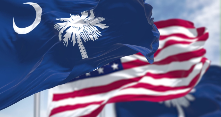 The South Carolina state flag waving along with the national flag of the US. South Carolina is a state in the coastal Southeastern region of the United States. Seamless loop in slow motion