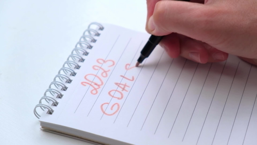 Female hand writes the numbers of 2023 and goals with pink felt-tip pen in white notebook. the concept of planning, motivation and setting goals for the coming year. close-up. slow motion. | Shutterstock HD Video #1091298867