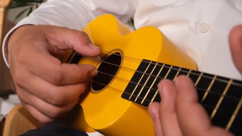 playing the ukulele, Close-up of man in white shirt playing yellow ukulele