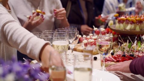 Стоковое видео: Waiter pouring glasses with champagne on catering service on banquet table with canape snacks in restaurant or hotel. Food set on birthday, wedding celebration or business conference event venue.