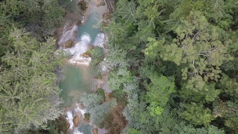 Aerial flyover of stunning Kuang Si waterfall in lush jungle of Laos