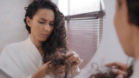 Upset sad young woman distressed by damaged hair frustrated about split ends girl worried about loss brittle dry hair hormone problem vitamin deficiency reflecting in mirror haircare treatment concept - Powered by Shutterstock - Get 15% off with code: PIKWIZARD15