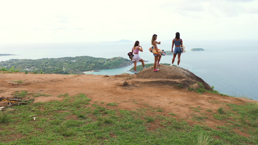 Group of Healthy Asian woman skater skating and hiking to mountain peak at tropical island on summer travel vacation. Female friends enjoy outdoor activity lifestyle adventure extreme sport together