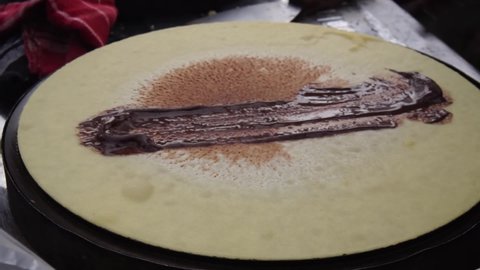 The process of making crepes is filled with spread of chocolate and cheese. Thin pancakes, blini. Sweet dessert. close-up view